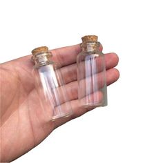 two small glass bottles with corks in the palm of a person's hand