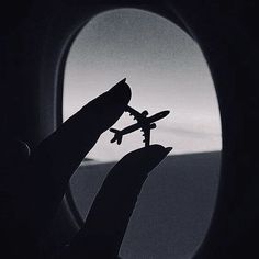 a person holding a small toy airplane in their hand while looking out an airplane window