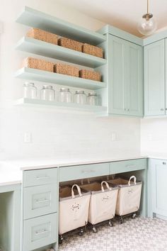 a kitchen with blue cabinets and baskets on the shelf above it is filled with bottles