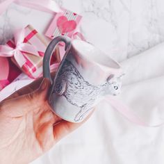 a hand holding a coffee cup with a bear on it next to some wrapped presents