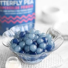 a glass bowl filled with blue candies next to a bottle of sterefy pa