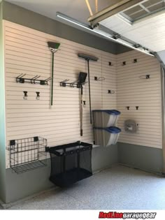 the inside of a garage with several different items hanging on the wall and two bins in front of them