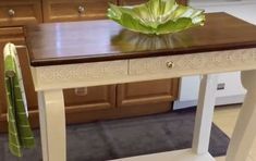 a white table with a green leaf on top of it in the middle of a kitchen