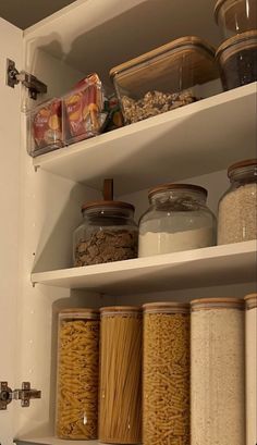 an organized pantry with lots of food in glass jars and cereal on the bottom shelf