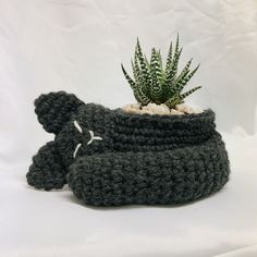 a crocheted pot holder with a plant in it and a stuffed animal on top