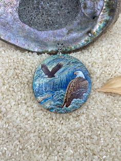 a necklace with an eagle sitting on top of it next to a bowl filled with rice