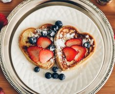 two heart shaped waffles topped with strawberries and blueberries on a plate