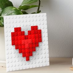 a heart made out of legos sitting on a table next to a potted plant