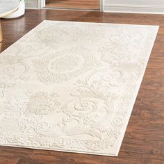 a large white rug on the floor in a room with hardwood floors and wooden stairs