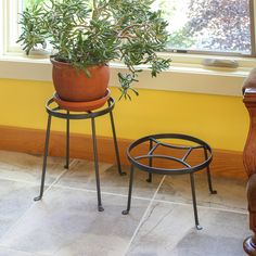 two potted plants sitting next to each other on top of stools in front of a window