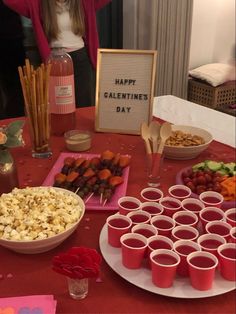 a table topped with lots of food next to cups and bowls filled with candy bars