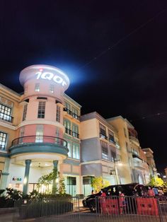 the front of a hotel at night with cars parked in front and on the street