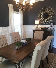 a dining room table with beige chairs and a chandelier hanging from the ceiling