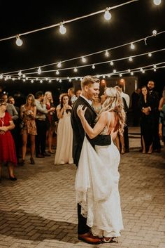 a bride and groom share their first dance at their wedding reception in front of the crowd