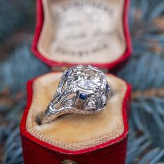 an antique diamond ring sits in a red velvet box