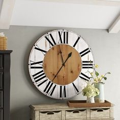 a large clock mounted to the side of a wall next to a chest of drawers