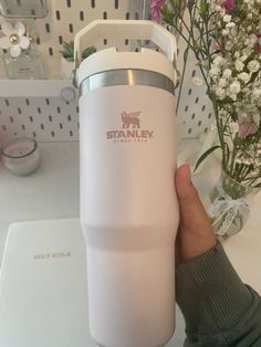 a person holding a white travel mug in their hand