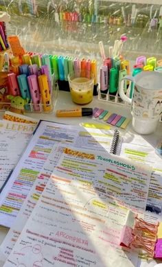 a table topped with lots of different types of pens and paper on top of it