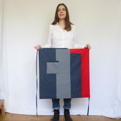 a woman holding a piece of fabric with the letter f on it in front of a white background