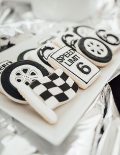 decorated cookies are sitting on a plate with silver foil around the edges and black and white designs