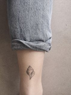 a woman's foot with a small tattoo on her left leg and a seashell in the middle