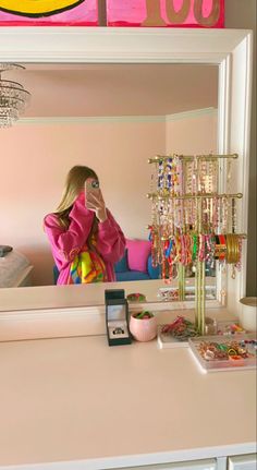 a woman taking a selfie in front of a mirror with jewelry on the counter