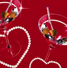 two wine glasses with hearts and pearls in them on a red background, decorated with the word love