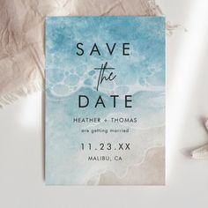 save the date card with starfish and seashells on white fabric next to it