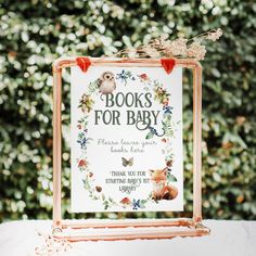 a sign that reads books for baby with an owl and flowers in the frame on a table