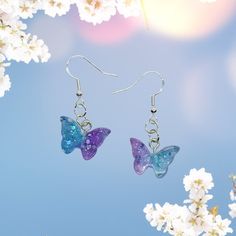 "Pretty aesthetic butterfly drop earrings. Resin pastel purple & blue glitter with ear wires. These are lightweight and have a touch of sparkle. Choose from stainless steel or sterling silver plated ear wires. Drop: approx. 1\" Height: approx. 0.5\" Width: approx. 0.6\"" Butterfly Earrings Aesthetic, Purple Glitter Earrings For Gift, Fairycore Butterfly Earrings For Gift, Cute Danish Butterfly Pastel Earrings, Multicolor Dangle Earrings In Kawaii Style, Purple Butterfly Charm Earrings For Gift, Blue Butterfly Earrings, Kawaii Hypoallergenic Drop Earrings, Aesthetic Butterfly