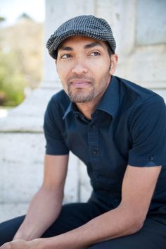 a man sitting on the ground wearing a hat and looking up at the camera with his eyes wide open