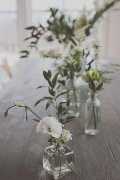 three vases filled with flowers on top of a wooden table