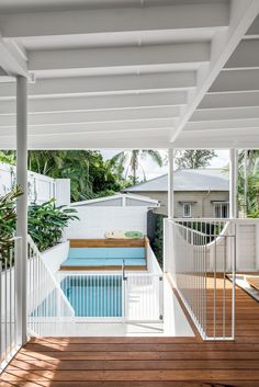 an outdoor swimming pool surrounded by wooden floors and white railings, with the sun shining through