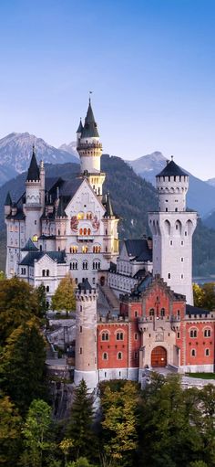 an old castle in the mountains surrounded by trees