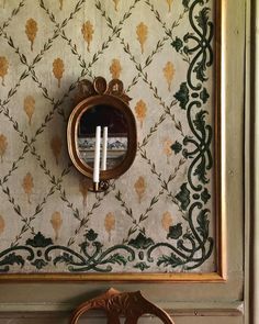 a mirror mounted to the side of a wall next to a chair with a candle in it