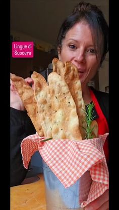 a woman is holding up some bread sticks