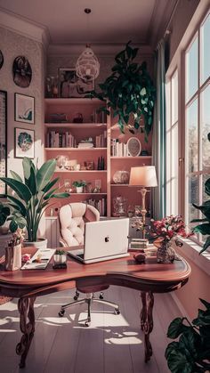 a desk with a laptop on it in front of a window filled with potted plants