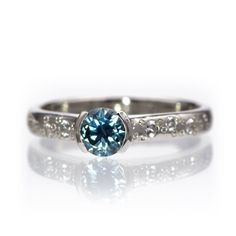 a white gold ring with a blue diamond