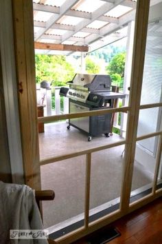 an open door leading to a patio with grilling equipment on the deck and outside