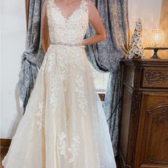 a woman standing in front of a window wearing a wedding dress