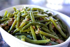 a white bowl filled with green beans and bacon