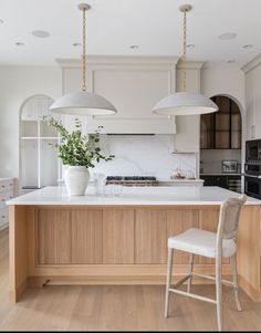 a kitchen with white cabinets and wooden counter tops, two pendant lights over the island