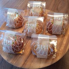 six wrapped sandwiches sitting on top of a wooden table next to each other in plastic bags