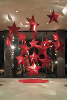 red stars are hanging from the ceiling in front of a large window with lights on it