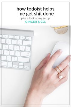 a woman's hand on top of a mouse next to a keyboard and computer