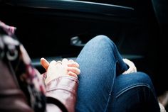 a person sitting in the back seat of a car with their hand on her lap