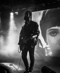 a man standing on top of a stage with a guitar in front of his face