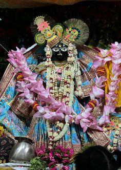 the statue is decorated with flowers and garlands on it's head, surrounded by other decorations