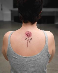 a woman with a pink flower tattoo on her back shoulder and behind her is a grey tank top