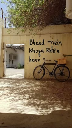 a bike parked next to a wall with graffiti on it's side and the words bheed mean khoya rha hon